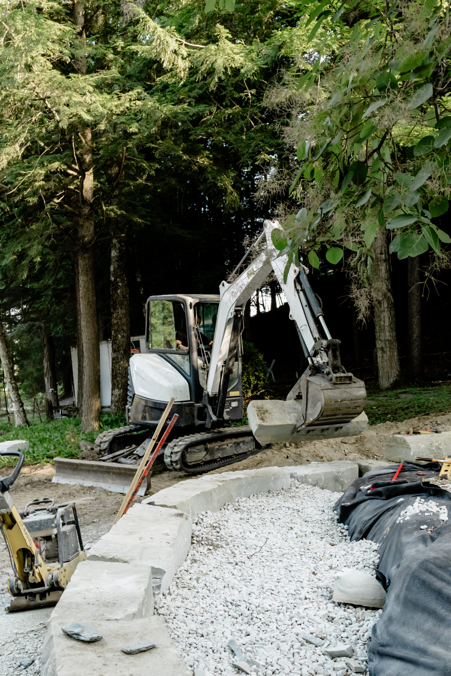 Mini-excavatrice au travail près d’un muret en construction