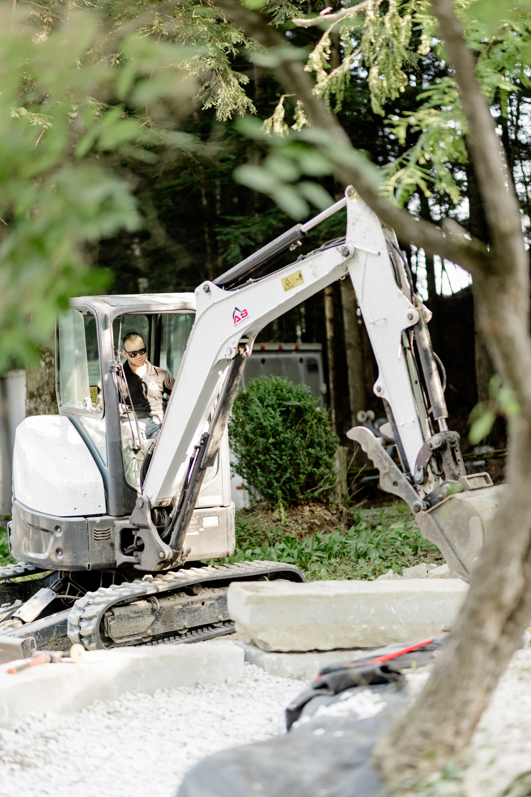 Mini-excavatrice qui travaille entre les arbres