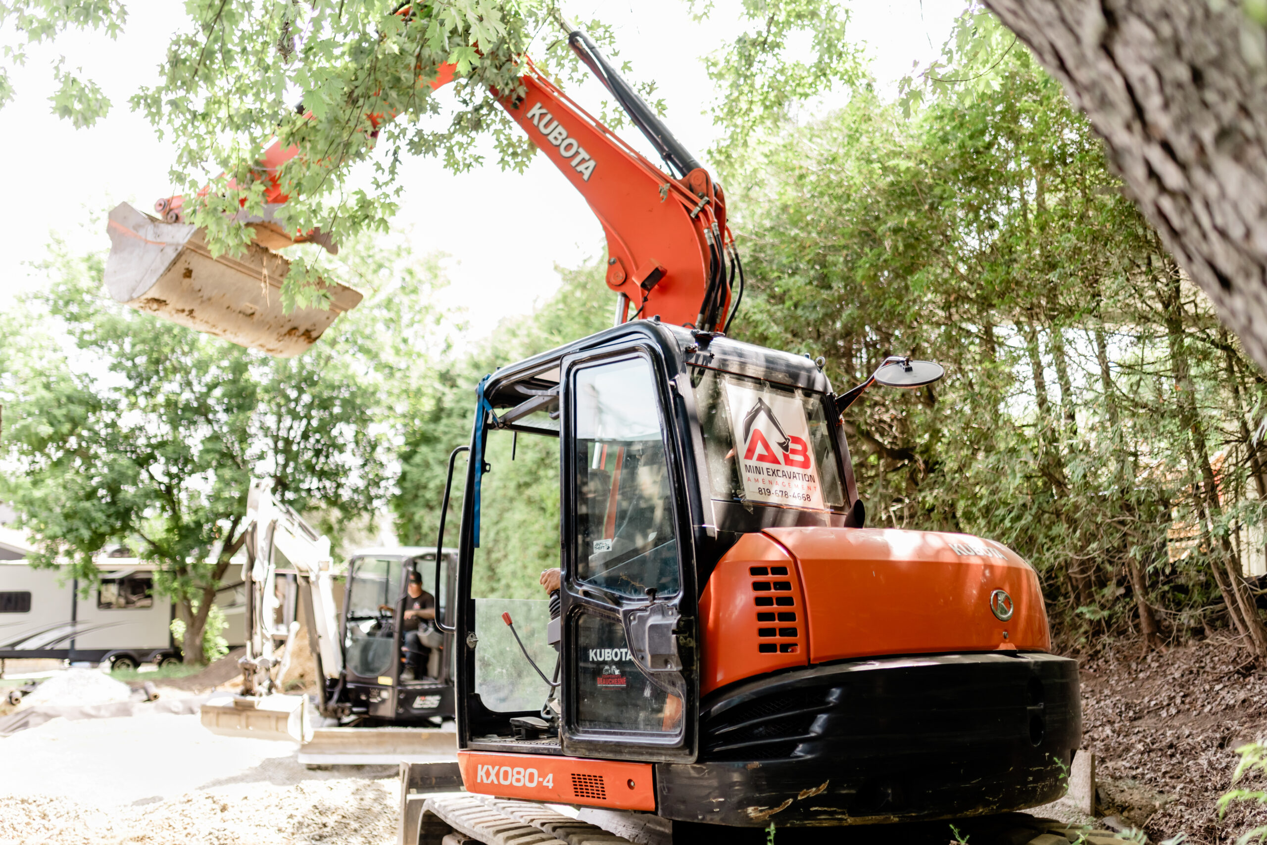 Excavatrice orange AB qui soulève une pierre
