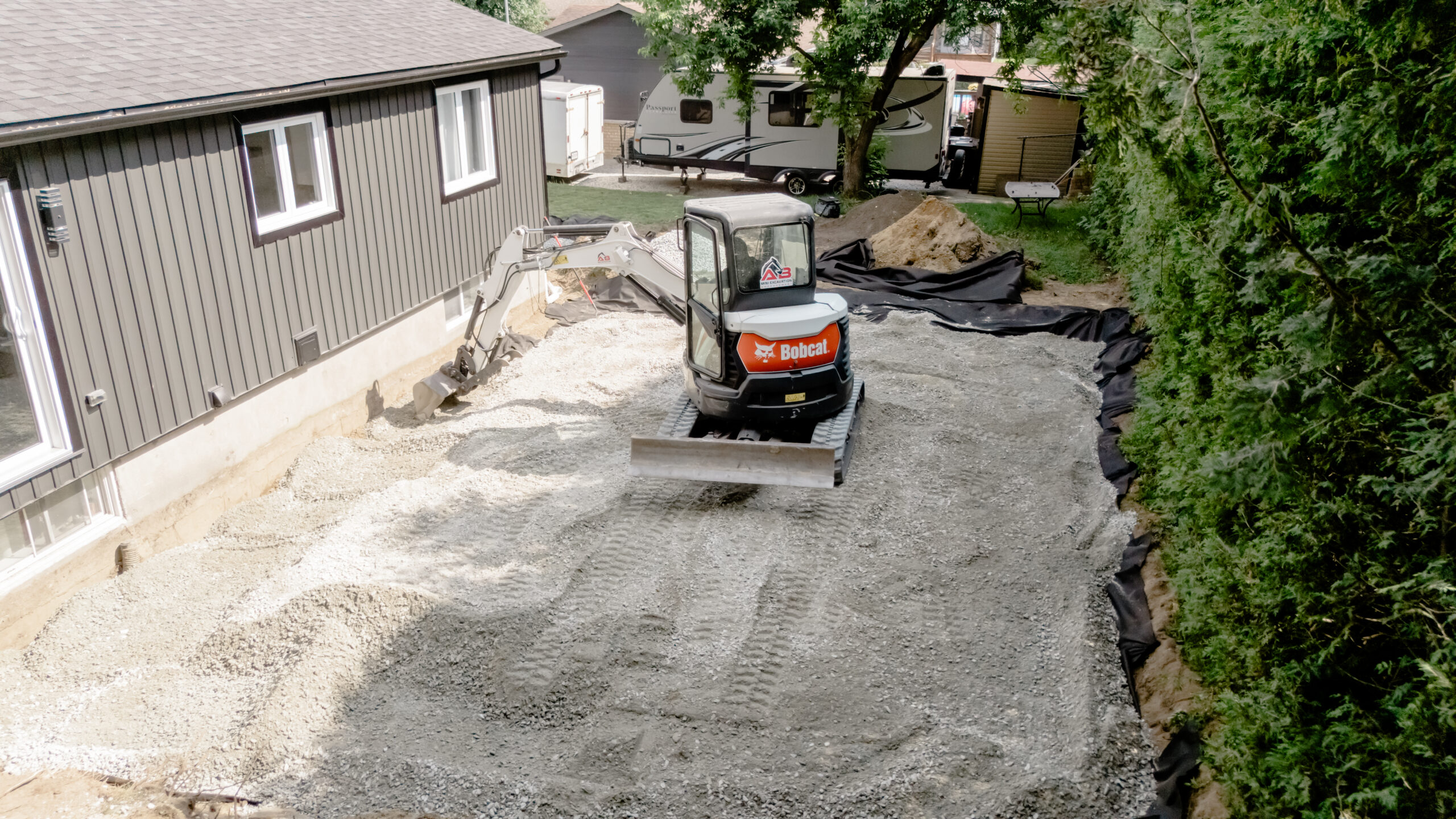 Mini-excavatrice sur une fondation granulaire près d’une maison