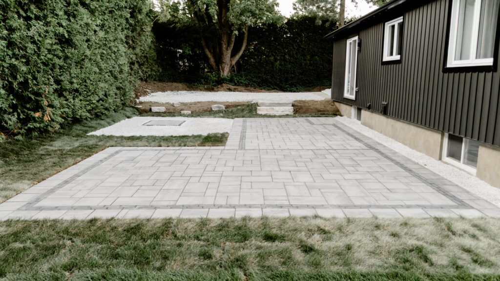 Patio en pavé uni terminé le long d’une maison