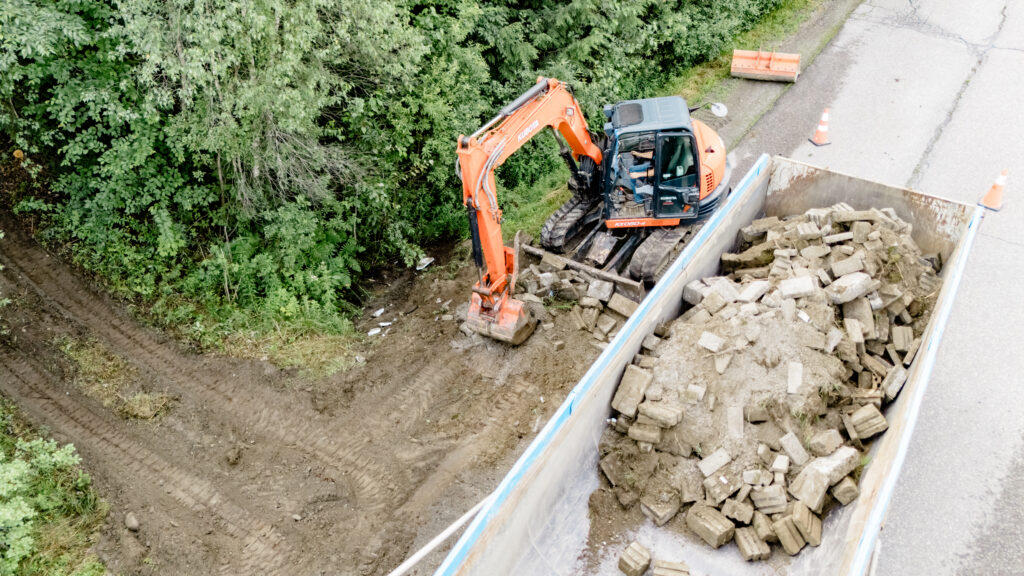 Excavatrice qui charge un camion de débris