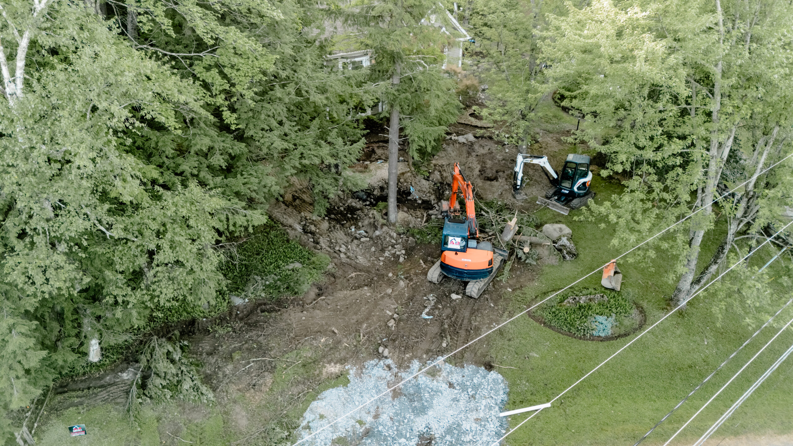 Mini-excavatrices au travail dans une cour boisée, vue du ciel